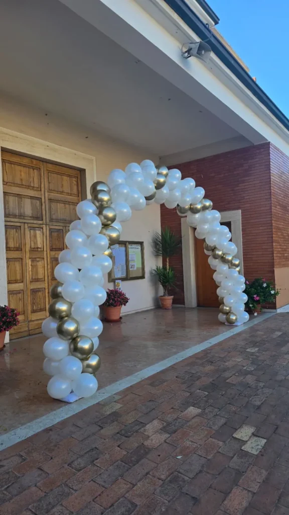 Arco di palloncini bianco e oro all'ingresso